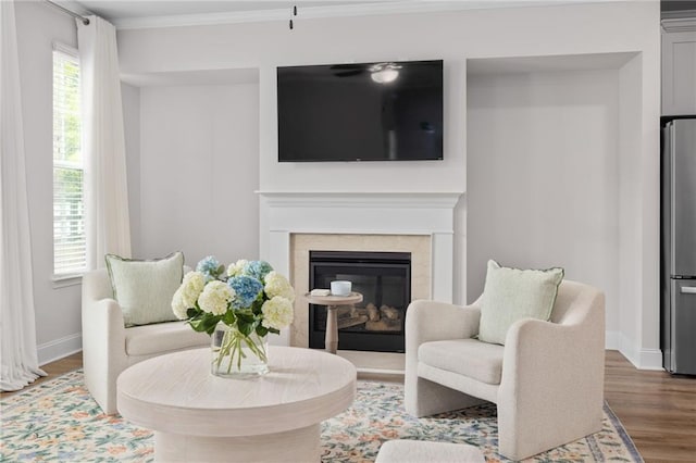 sitting room featuring baseboards, a premium fireplace, wood finished floors, and crown molding