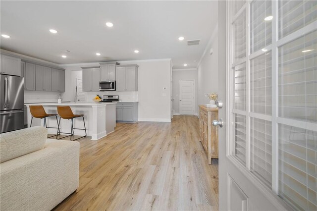 kitchen with stainless steel appliances, visible vents, gray cabinetry, open floor plan, and a sink