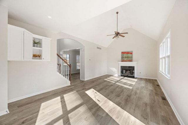 unfurnished living room with ceiling fan, dark hardwood / wood-style floors, vaulted ceiling, and a wealth of natural light