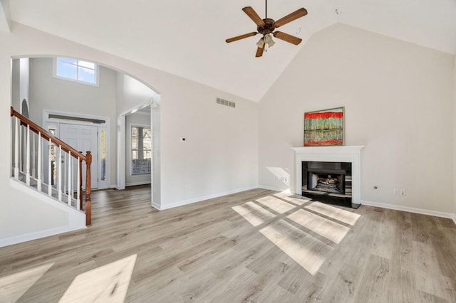 unfurnished living room with ceiling fan, high vaulted ceiling, and light hardwood / wood-style flooring