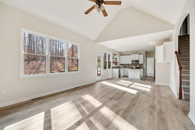 unfurnished living room with high vaulted ceiling, light hardwood / wood-style floors, and ceiling fan