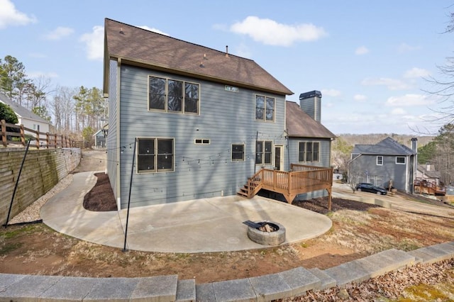 back of property with a wooden deck, a patio area, and a fire pit