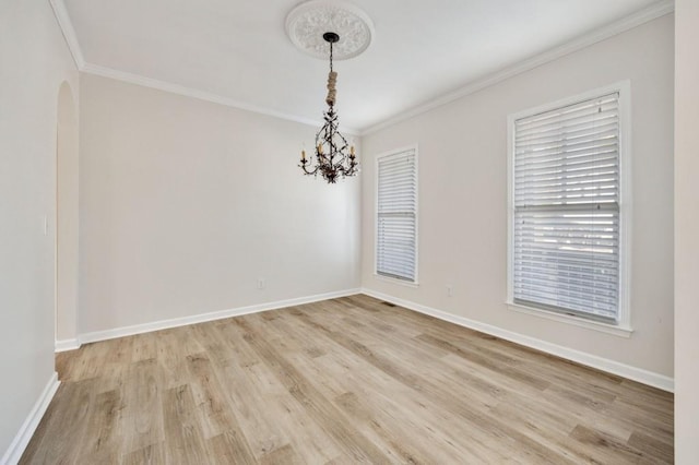 empty room with a notable chandelier, light hardwood / wood-style flooring, and ornamental molding