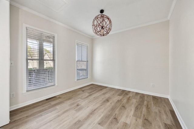 spare room featuring ornamental molding, a notable chandelier, and light wood-type flooring