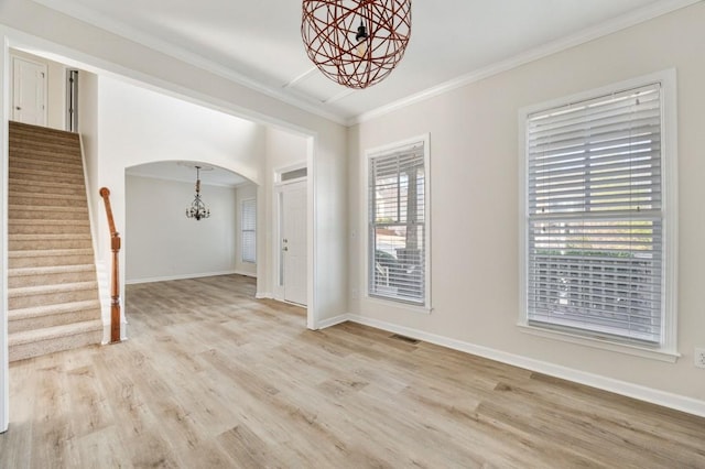 spare room featuring crown molding, light hardwood / wood-style floors, and a chandelier