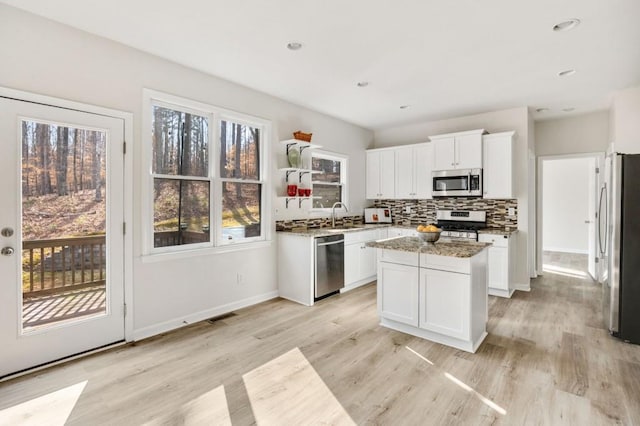 kitchen with a kitchen island, sink, white cabinets, light stone counters, and stainless steel appliances