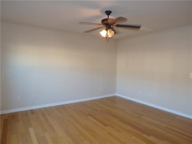 empty room featuring light wood-type flooring, baseboards, and a ceiling fan