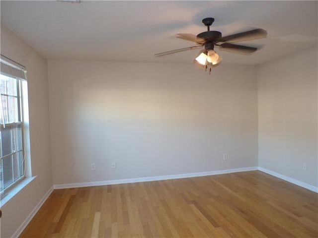 empty room with a ceiling fan, light wood-style flooring, and baseboards