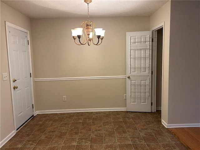 unfurnished dining area featuring a chandelier and baseboards