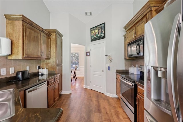 64 River Mist Cir, Jefferson, GA 30549 - kitchen featuring appliances with stainless steel finishes, dark countertops, wood finished floors, decorative backsplash, and lofted ceiling