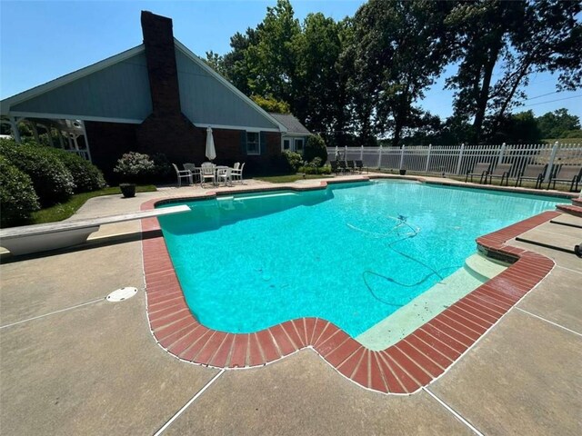 view of swimming pool featuring a diving board and a patio area