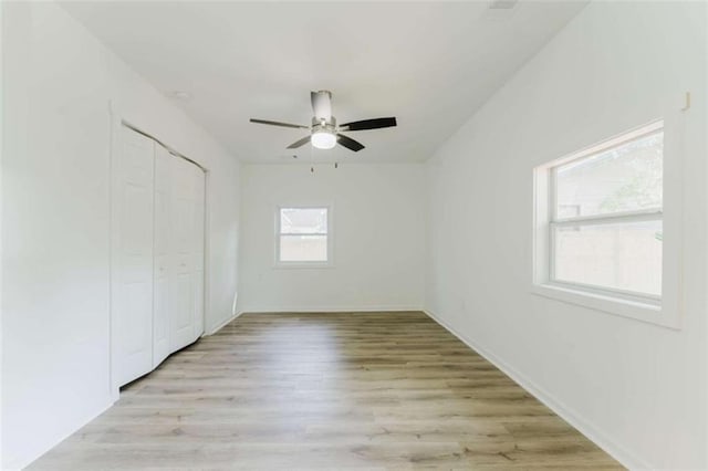 unfurnished bedroom with multiple windows, ceiling fan, and light hardwood / wood-style floors