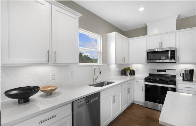 kitchen featuring white cabinets, a sink, stainless steel appliances, and tasteful backsplash