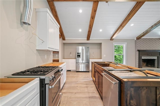 136 Ridgecrest Dr, Ball Ground, GA 30107 - kitchen featuring appliances with stainless steel finishes, light wood-type flooring, beam ceiling, white cabinets, and a fireplace