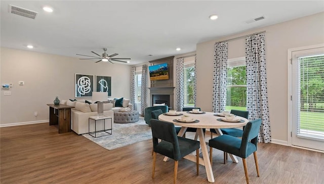 dining space featuring wood finished floors, plenty of natural light, ceiling fan, a fireplace, and recessed lighting