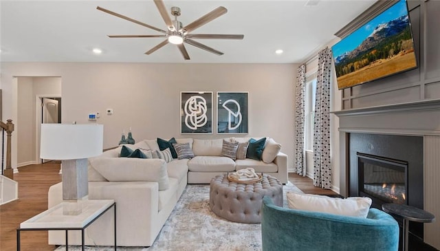 living room featuring a ceiling fan, wood finished floors, a glass covered fireplace, recessed lighting, and baseboards
