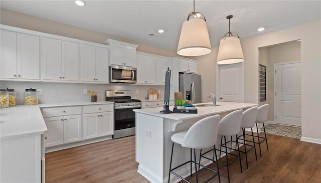 kitchen featuring stainless steel appliances, a sink, a kitchen island with sink, dark wood finished floors, and recessed lighting