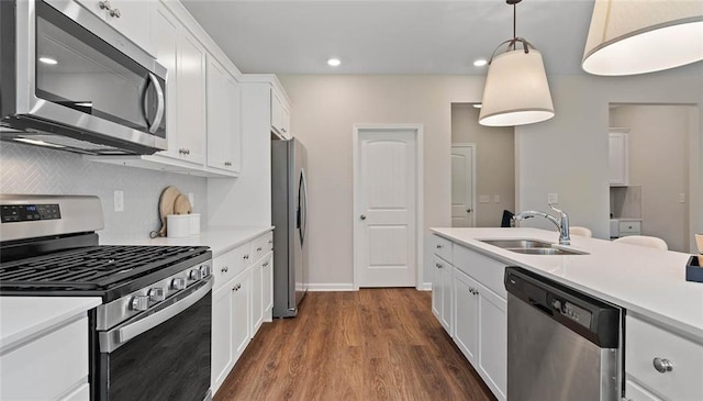 kitchen featuring stainless steel appliances, a sink, dark wood-type flooring, backsplash, and white cabinetry