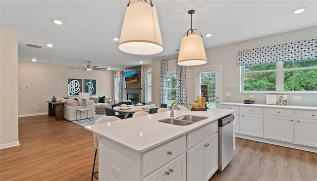 kitchen featuring light wood finished floors, dishwasher, light countertops, a sink, and ceiling fan