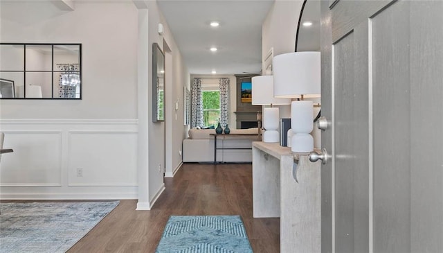 hall featuring a decorative wall, dark wood-style floors, and recessed lighting