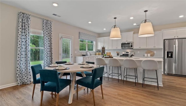 dining room featuring plenty of natural light, light wood-type flooring, recessed lighting, and baseboards