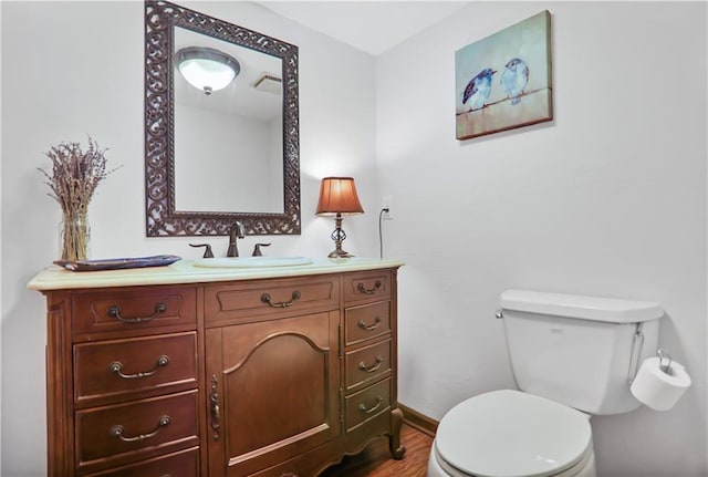 bathroom featuring baseboards, vanity, toilet, and wood finished floors