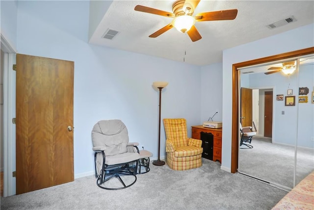 sitting room featuring carpet floors, visible vents, and a ceiling fan