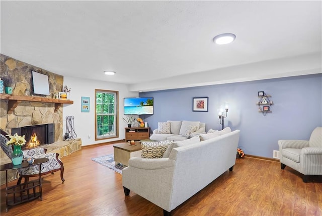 living area featuring a fireplace, wood finished floors, and baseboards