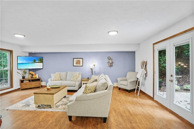 living room with french doors, baseboards, and light wood finished floors