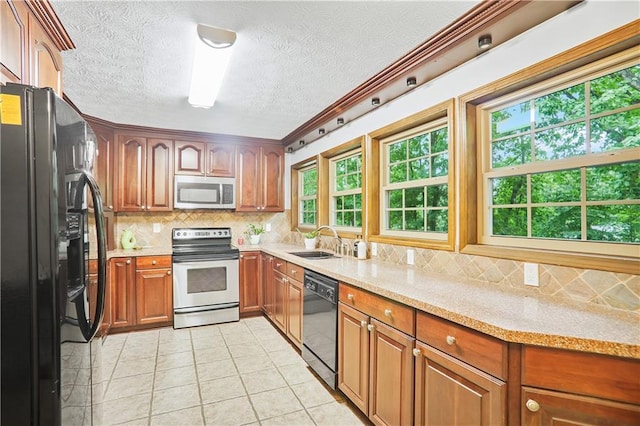 kitchen featuring light stone counters, brown cabinetry, a sink, and black appliances