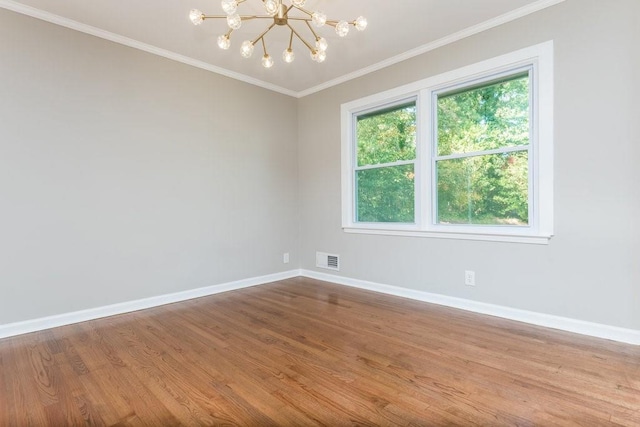 unfurnished room featuring ornamental molding, a notable chandelier, and hardwood / wood-style flooring