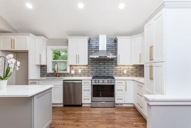 kitchen with stainless steel appliances, dark wood-type flooring, sink, wall chimney range hood, and white cabinets