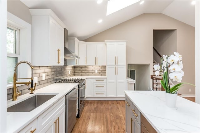 kitchen featuring white cabinets, stainless steel appliances, wall chimney exhaust hood, and sink