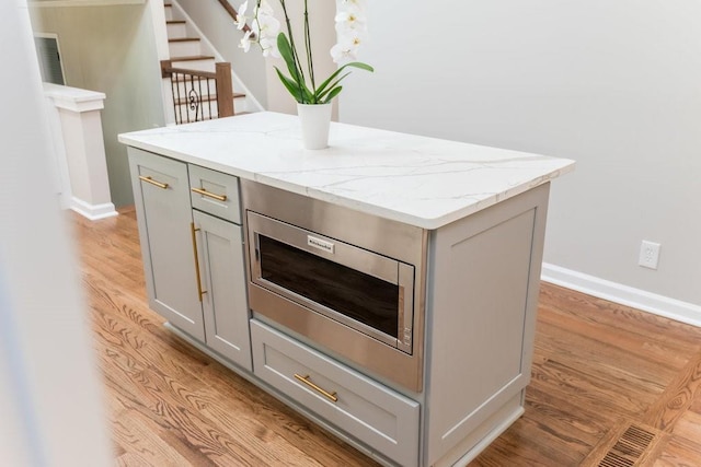 kitchen featuring gray cabinetry, a center island, and light wood-type flooring