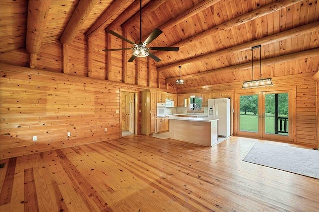unfurnished living room featuring lofted ceiling with beams, light wood-style flooring, wooden walls, and wooden ceiling