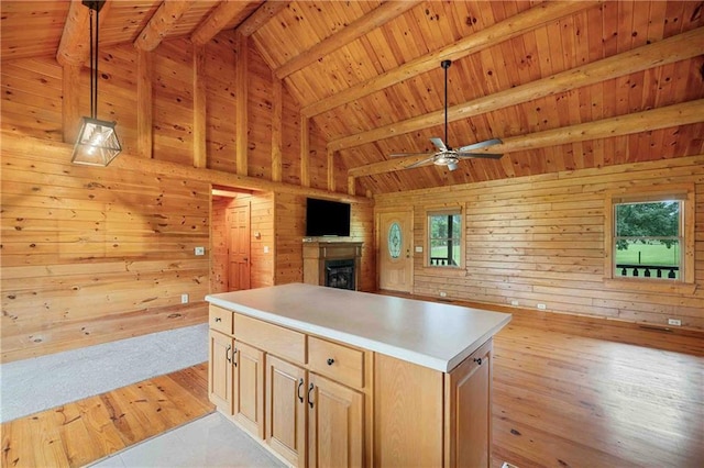 kitchen with beam ceiling, a fireplace, open floor plan, ceiling fan, and wooden ceiling