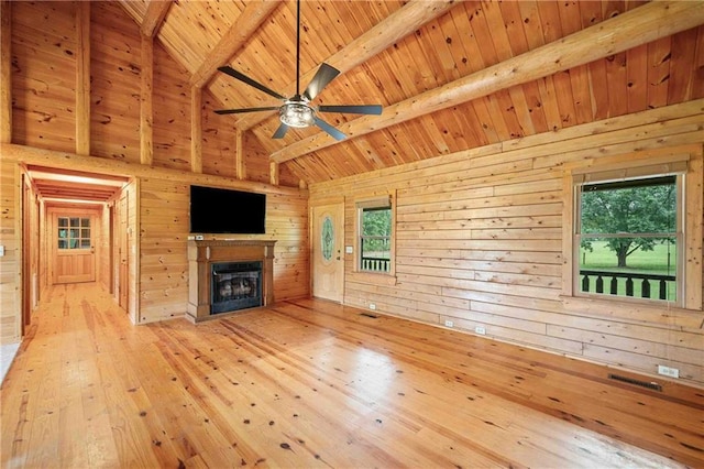 unfurnished living room with wood ceiling, a fireplace, hardwood / wood-style flooring, beam ceiling, and wooden walls