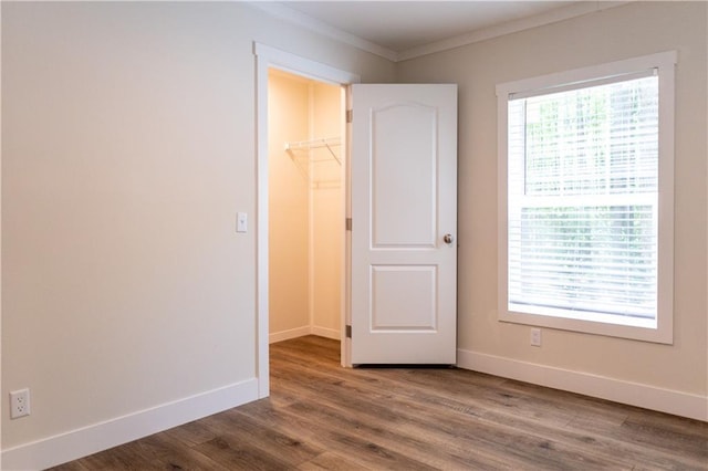 spare room featuring crown molding, baseboards, and wood finished floors