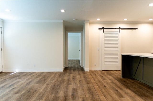 interior space with recessed lighting, a barn door, ornamental molding, and wood finished floors