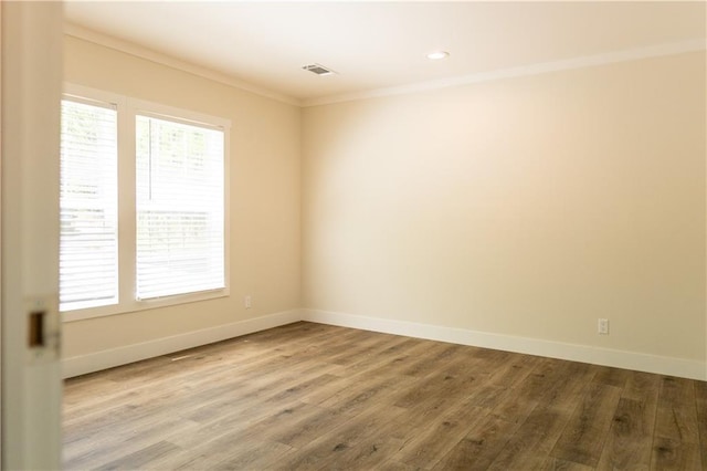 empty room with visible vents, ornamental molding, baseboards, and wood finished floors