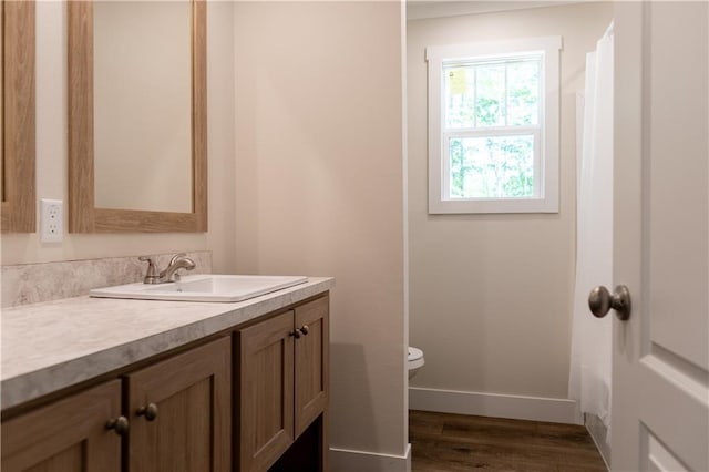 bathroom with vanity, baseboards, toilet, and wood finished floors