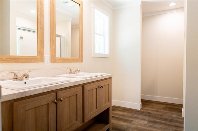 full bathroom with double vanity, a sink, baseboards, and wood finished floors