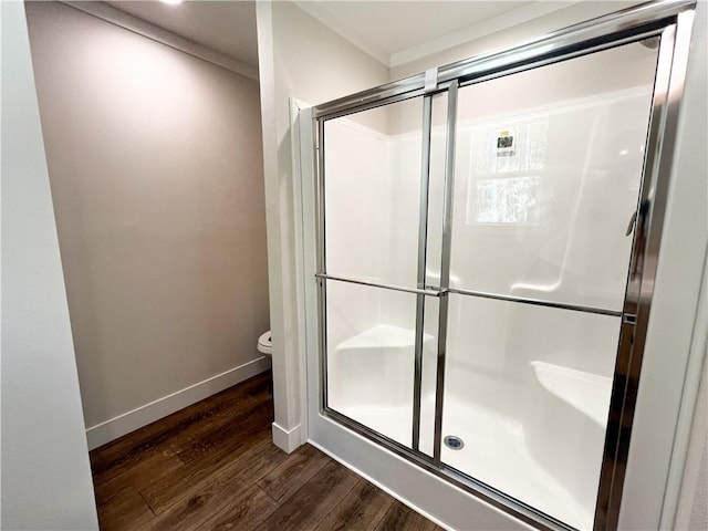 bathroom featuring toilet, baseboards, a shower stall, and wood finished floors