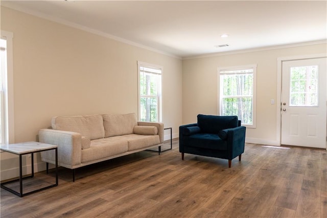 living area with dark wood-style flooring, baseboards, visible vents, and ornamental molding