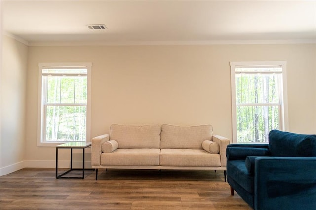 living room featuring baseboards, ornamental molding, wood finished floors, and visible vents