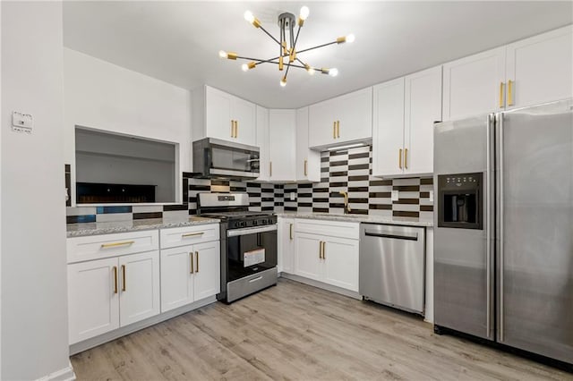 732 Jamestown Xing, Jonesboro, GA 30238 - kitchen with stainless steel appliances, white cabinetry, a chandelier, and decorative backsplash