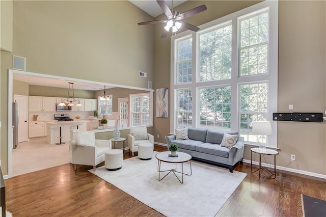 5115 Amberden Hall Dr, Suwanee, GA 30024 - living area featuring a high ceiling, baseboards, a ceiling fan, light wood-type flooring, and a chandelier