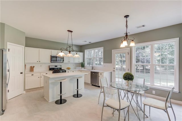 5115 Amberden Hall Dr, Suwanee, GA 30024 - kitchen with stainless steel appliances, decorative backsplash, light countertops, white cabinetry, and a kitchen island