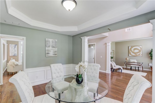 5115 Amberden Hall Dr, Suwanee, GA 30024 - dining space featuring a raised ceiling, ornate columns, wood finished floors, crown molding, and wainscoting