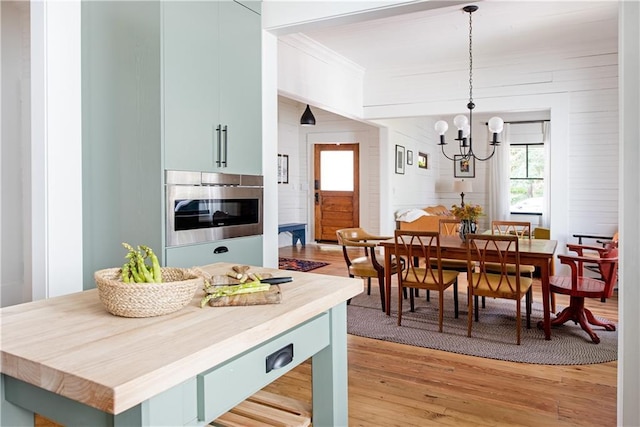 dining space with light wood-style floors, crown molding, and an inviting chandelier